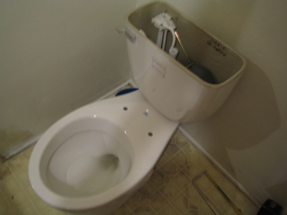 Toilet tank with internal mechanism visible, and bowl. Some text is visible inside the tank