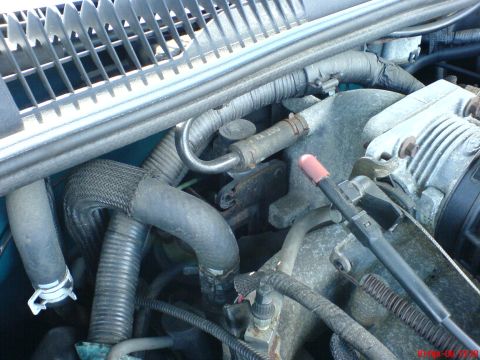 1994 Ford Thunderbird - Close-up view of an engine bay, showing various hoses and components. Text on one hose indicates 'DOT KXX 300'.