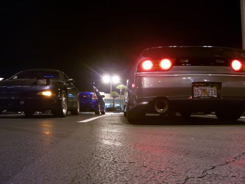 1994 Ford Probe - Multiple cars are parked in a lot at night, illuminated by streetlights and their own brake lights.