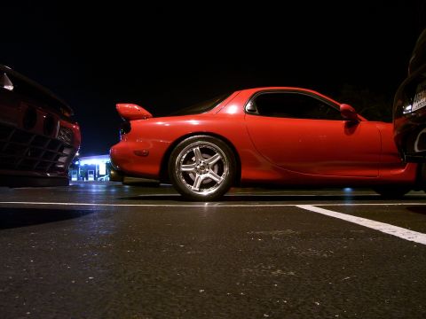 1994 Ford Probe - A red sports car is parked at night next to another vehicle.