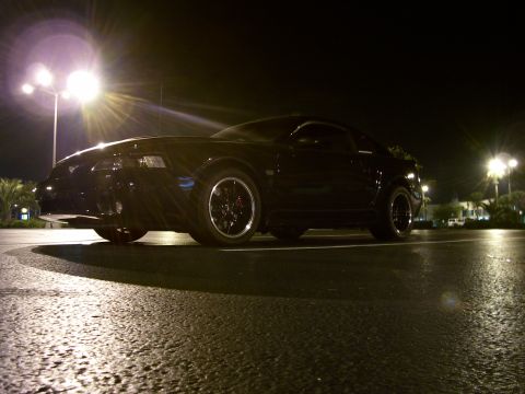 1994 Ford Probe - Black coupe with aftermarket wheels parked at night under streetlights.