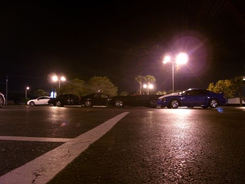 1994 Ford Probe - Multiple vehicles are parked in a lot under artificial lighting at night.