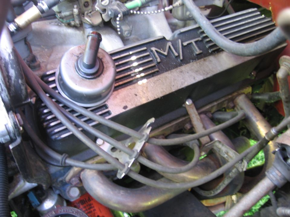 Engine valve cover with M/T lettering, spark plug wires, and exhaust manifold