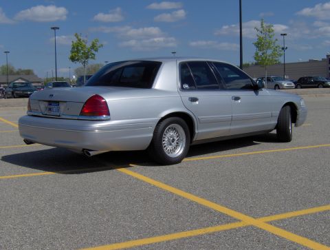 2002 Ford Crown Victoria - Rear view of a silver 2002 Ford Crown Victoria parked in a lot on a sunny day.