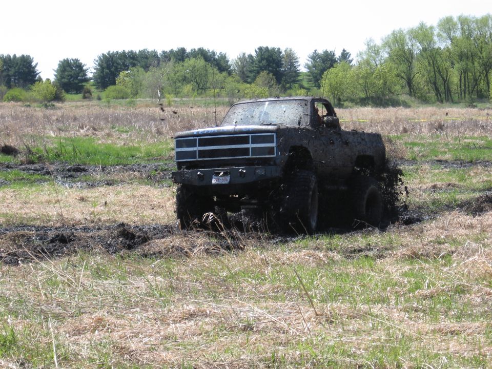 Mud-covered pickup truck driving through a muddy field