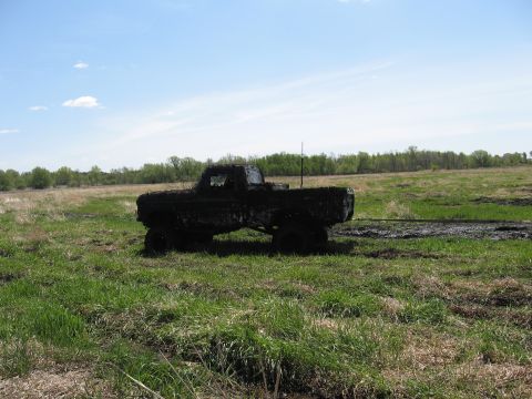 1977 Ford F-150 - Muddy 1977 Ford F-150 sits in a field under a partly cloudy sky.