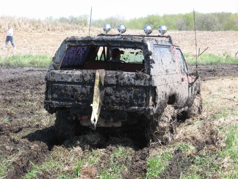 1977 Ford F-150 - Mud-covered SUV stuck in a muddy field with a tow strap hanging from the rear.