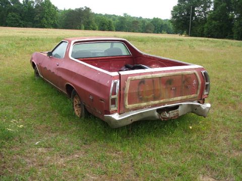 1972 Ford Ranchero - 1972 Ford Ranchero pickup truck sits in a field, showing its rear end and bed.