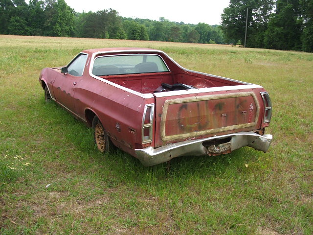 Red 1972 Ford Ranchero parked in a grassy field, rear view