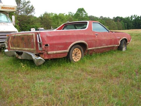 1972 Ford Ranchero - This red pickup truck appears to be a Ford Ranchero, but it's not a 1972 model. It's parked in a field next to an RV.