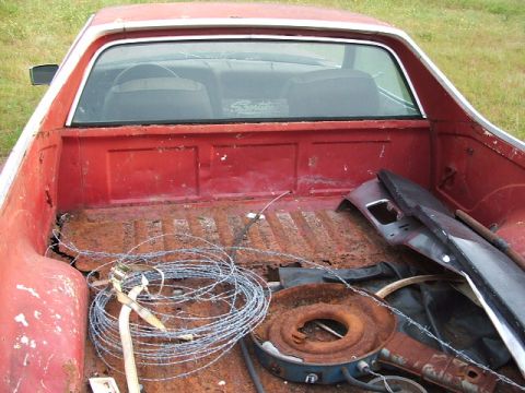 1972 Ford Ranchero - The bed of a red 1972 Ford Ranchero pickup truck is filled with barbed wire and various car parts.