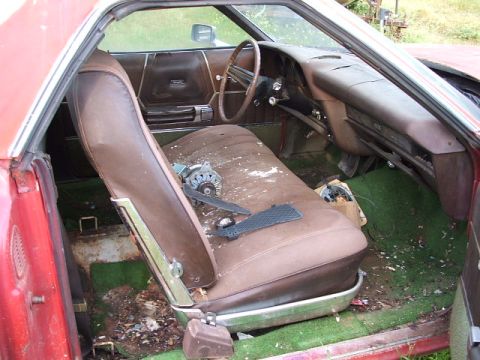 1972 Ford Ranchero - The interior of a vehicle shows worn brown seats and green carpet, with an alternator resting on the passenger seat.