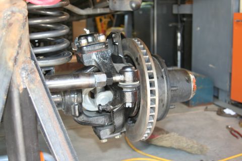 1992 Ford Bronco - This image shows a close-up of a vehicle's front axle assembly, including the steering components and brake rotor.