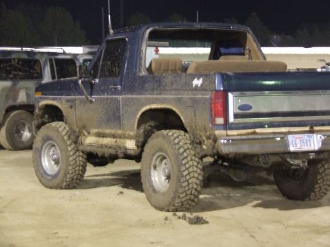 1986 Ford Bronco - This mud-covered 1986 Ford Bronco has its top removed and is seen from the rear.