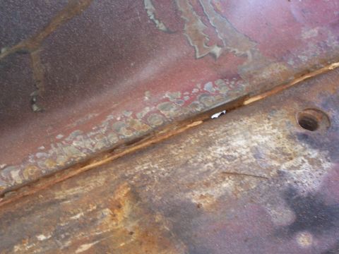 1978 Ford Bronco - Close-up view of a corroded metal panel, possibly from a vehicle's undercarriage or interior.