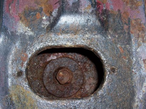 1978 Ford Bronco - This image shows a heavily rusted metal component with a bolt and washer, likely part of a vehicle's undercarriage.