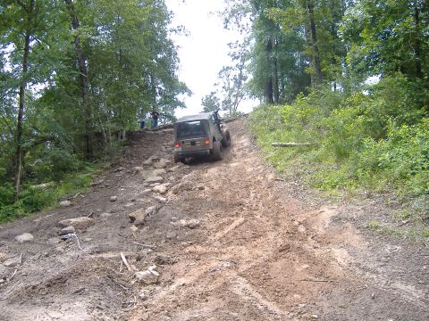 2004 Jeep Wrangler - A Jeep Wrangler navigates a challenging off-road trail through a wooded area.