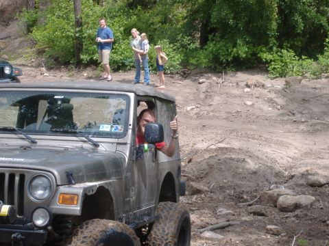 2004 Jeep Wrangler - A driver gives a thumbs up from a Jeep Wrangler during an off-road excursion with spectators watching.