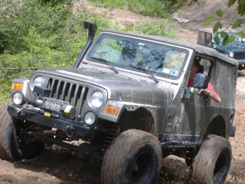 2004 Jeep Wrangler - This Jeep TJ is equipped for off-roading with a snorkel and winch, navigating a muddy trail.
