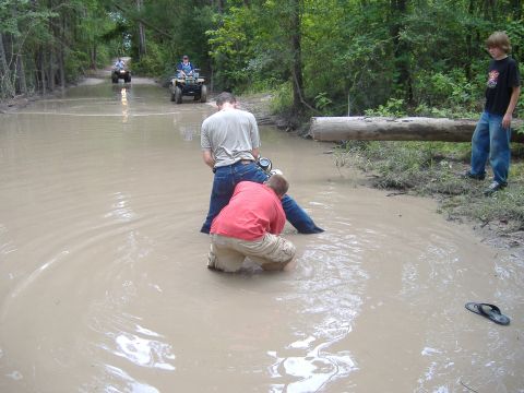 2004 Jeep Wrangler - ATVs navigate a muddy trail with water crossings and wooded surroundings.