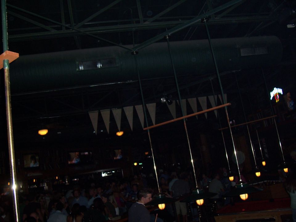 Interior of a bar with pool table lights hanging and people gathered