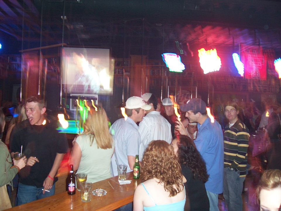 People gathered around a bar with drinks and a projection screen in the background