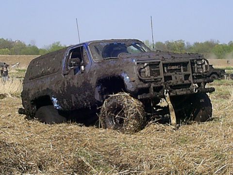 1994 Ford F-250 - Mud-covered GMC SUV stuck in a grassy field with its front grille visible.