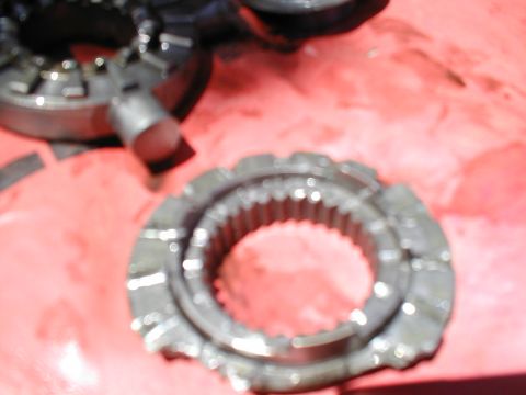 1979 Ford Bronco - Close-up of metal gears, likely from a transmission or differential, on a red background.