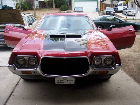 1972 Ford Ranchero - A red 1970s Ford Ranchero is parked with its doors open, a black hood scoop and a "FORD RACING" license plate.