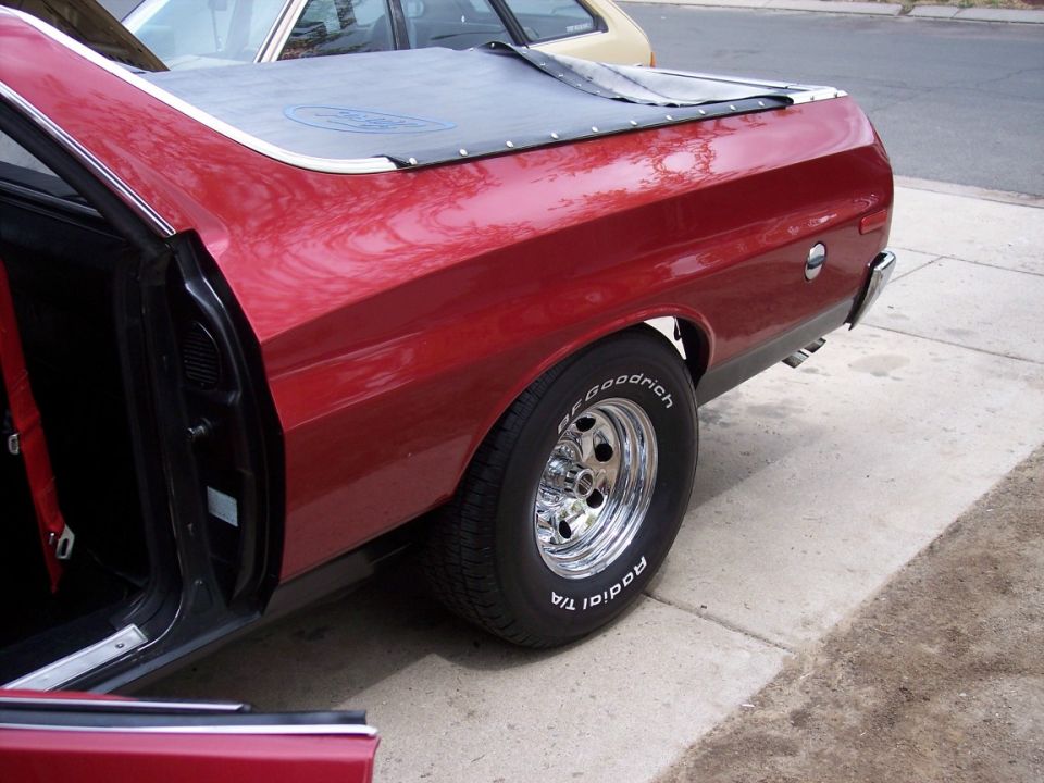 Rear quarter of maroon classic car with chrome wheel and BFGoodrich white-letter tire