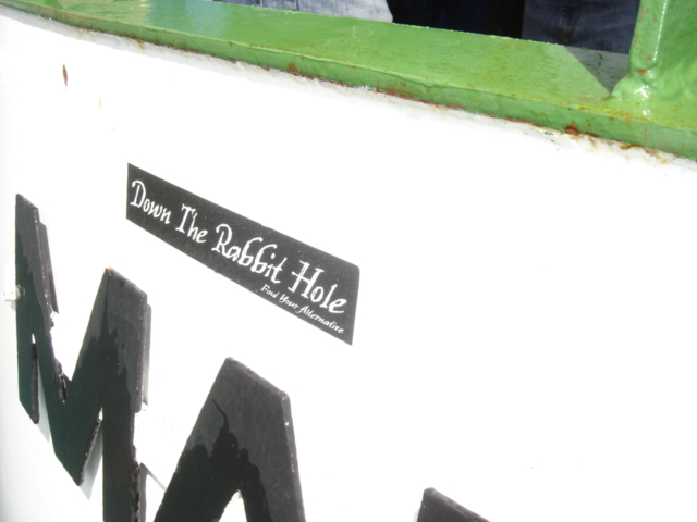 White surface with black lettering 'Down The Rabbit Hole' sticker and part of large black letters