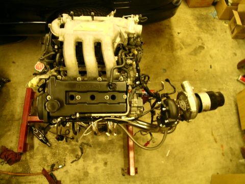 1995 Ford Probe - A Mazda engine is shown on a stand, modified with a turbocharger and various engine components.