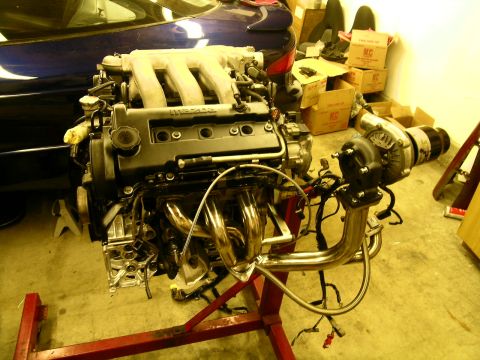 1995 Ford Probe - A Mazda V6 engine, modified with a turbocharger, is displayed on a red engine stand.