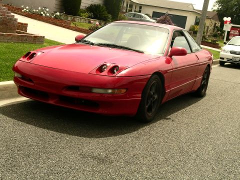 1993 Ford Probe - A red 1993 Ford Probe is parked on a residential street with a white car in the background.