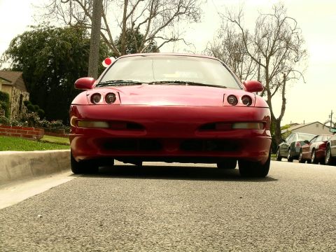 1993 Ford Probe - A red 1993 Ford Probe is parked on a residential street, viewed from a low angle.