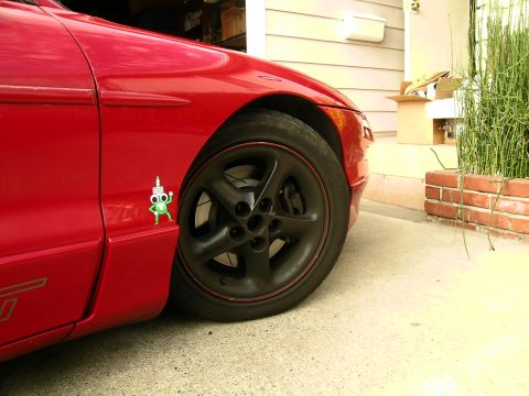 1993 Ford Probe - A close-up view of the front fender and wheel of a red sports car.
