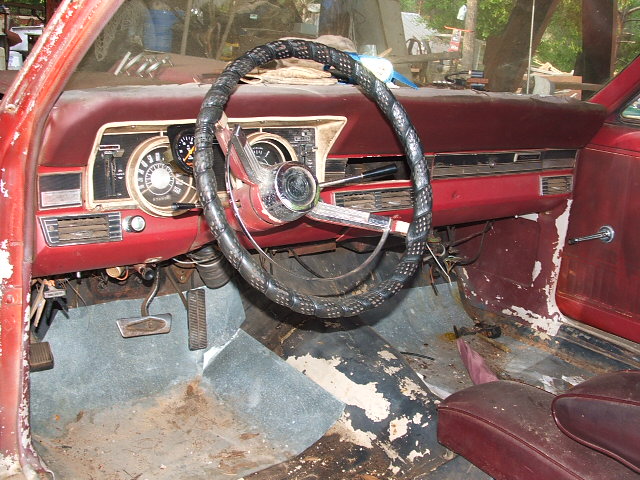 Worn red interior of a 1960s project car with lace-wrapped wheel
