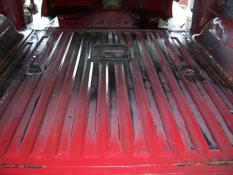 1978 Ford Bronco - The ribbed flooring and tie-down points are visible in the interior of this red truck bed.