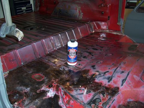 1978 Ford Bronco - Vehicle interior floor pan with rust damage and a can of primer, likely during a restoration project.