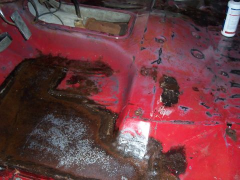 1978 Ford Bronco - The interior floor pan of a vehicle shows extensive rust damage and areas that have been patched.