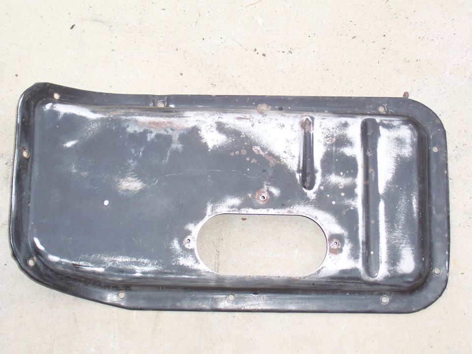 Dark gray metal plate with oval cutout and mounting holes, showing wear and rust spots