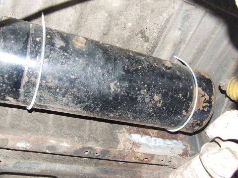 1986 Ford Bronco - A black air tank is secured to the undercarriage of a vehicle with wire straps.