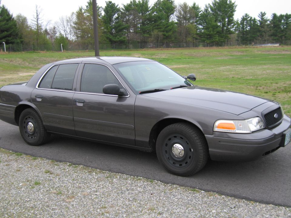 Dark gray sedan, 3/4 front view. Later model Crown Victoria