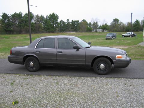 1991 Ford LTD Crown Victoria - Side profile of a gray Ford Crown Victoria sedan parked outdoors on a cloudy day.