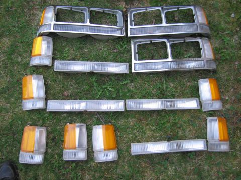 1991 Ford LTD Crown Victoria - Various vehicle lighting components are displayed on a grassy surface, likely for sale or storage.