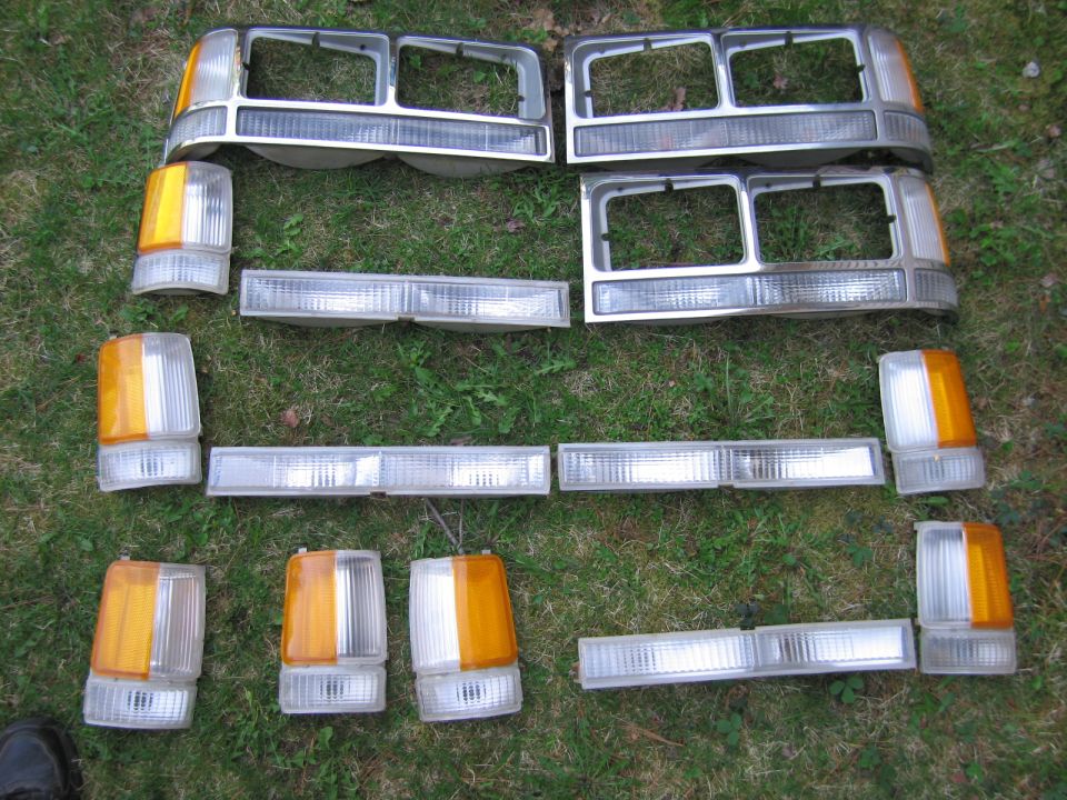 Collection of car headlights and turn signal lights laid out on grass
