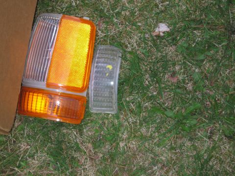 1991 Ford LTD Crown Victoria - Several vehicle lights, including amber turn signals and clear marker lenses, lie on a grassy surface.