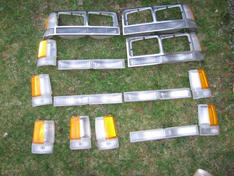 1991 Ford LTD Crown Victoria - Assorted car lights and grilles are laid out on a grassy surface.