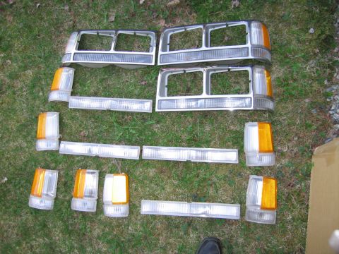 1991 Ford LTD Crown Victoria - Collection of car headlights and amber turn signal lenses arranged on a grassy surface.