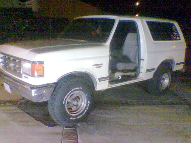 White SUV parked outside with driver's door open. Tires say BFGoodrich All-Terrain